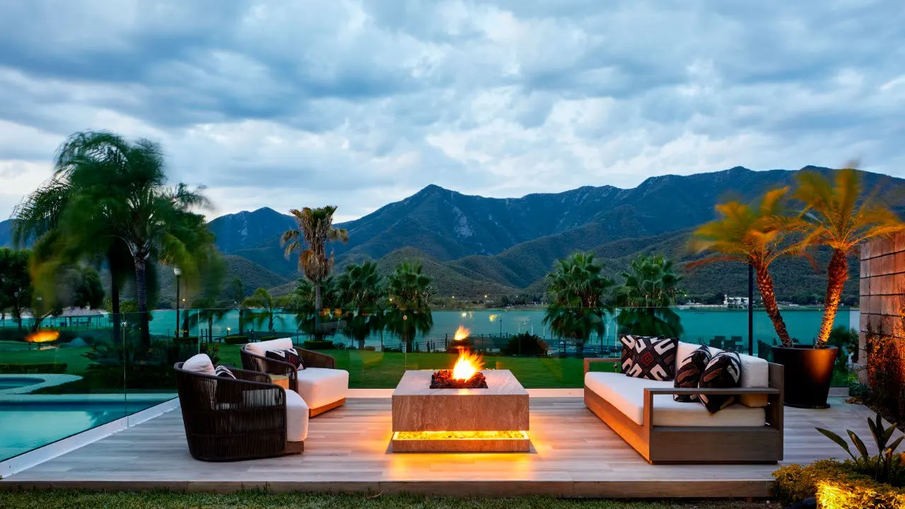 Terraza con fogatero de piedra y sala exterior frente al lago y la sierra